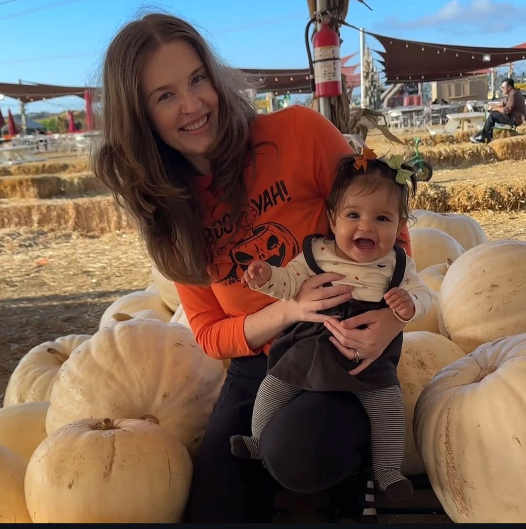 Joy smiling with her daughter at a pumpkin patch